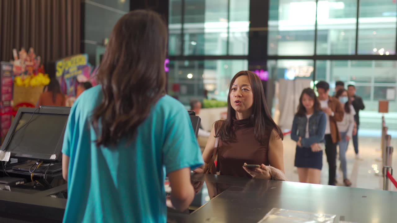 详情图-亚洲华人女性顾客在电影院售票处购买电影票，非接触式支付
