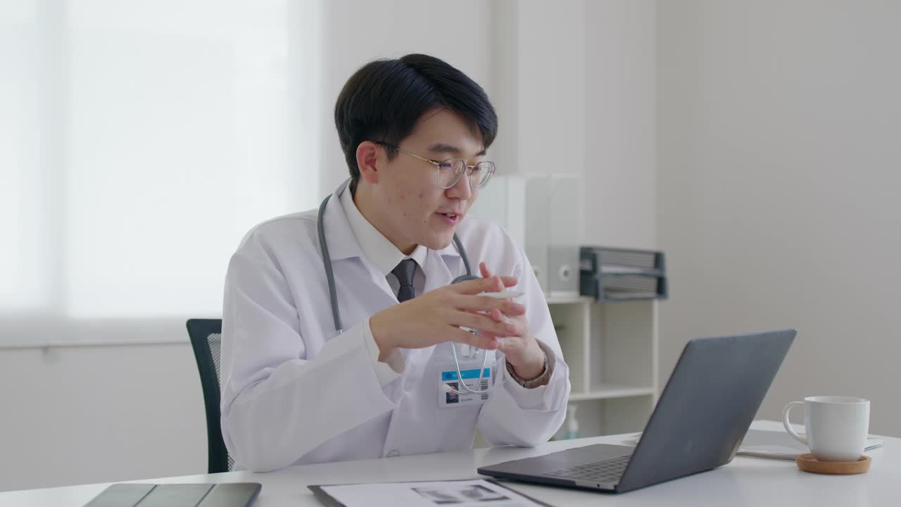 友好的亚洲医生男子视频呼叫在线交谈计算机远程健康。