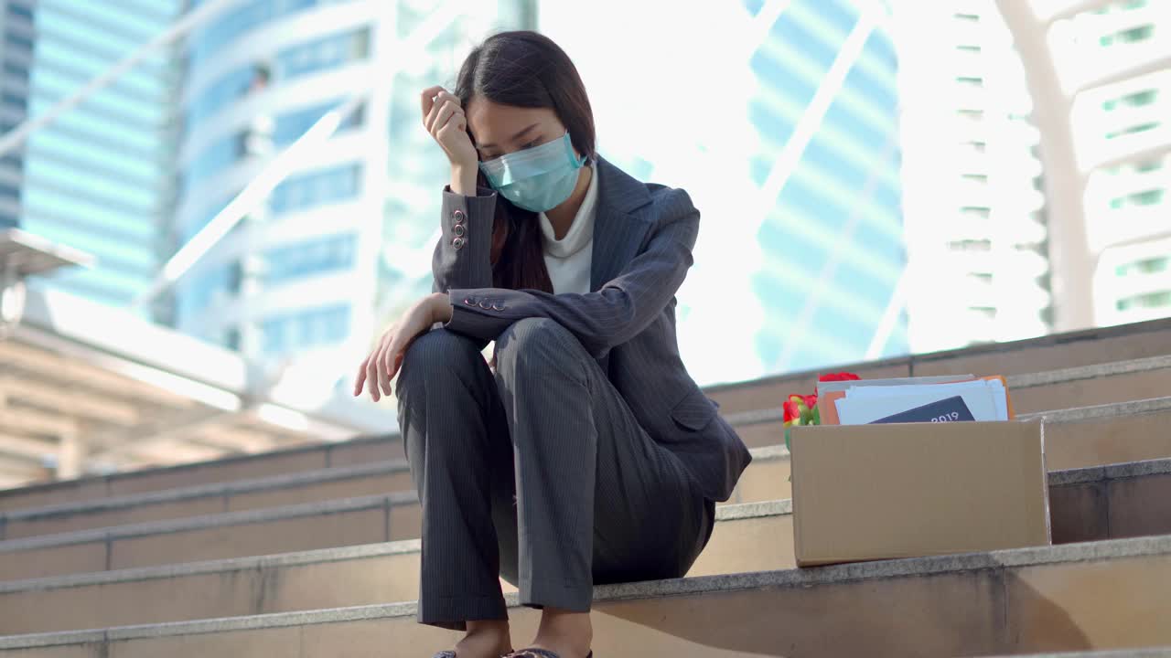 在公司裁员后，一个沮丧的女人拿着一个装着办公用品的盒子
