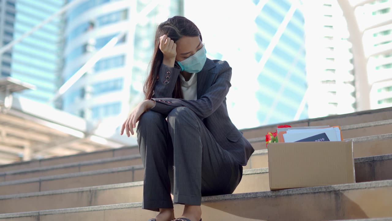 详情图-在公司裁员后，一个沮丧的女人拿着一个装着办公用品的盒子