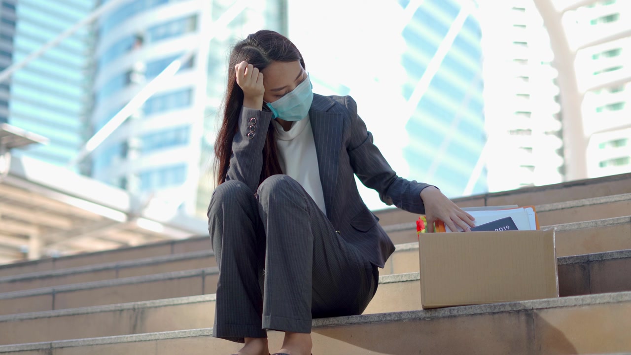 详情图-在公司裁员后，一个沮丧的女人拿着一个装着办公用品的盒子