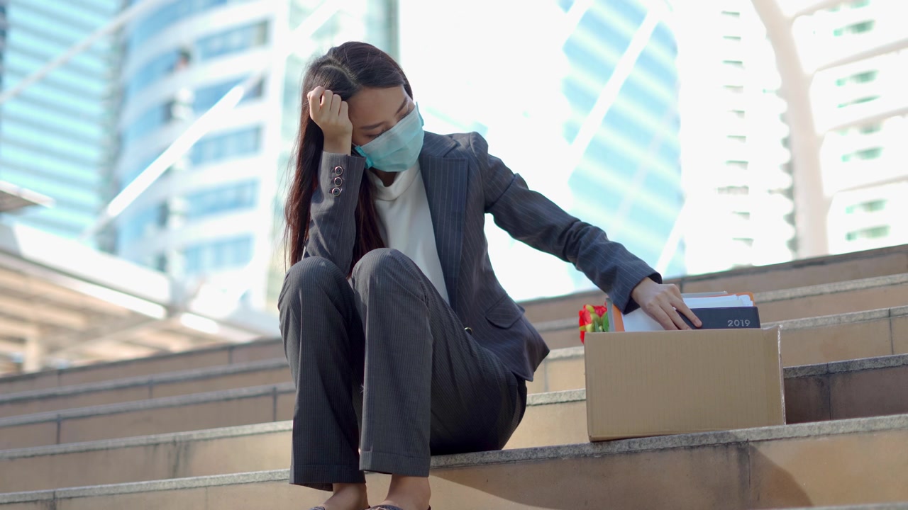 详情图-在公司裁员后，一个沮丧的女人拿着一个装着办公用品的盒子