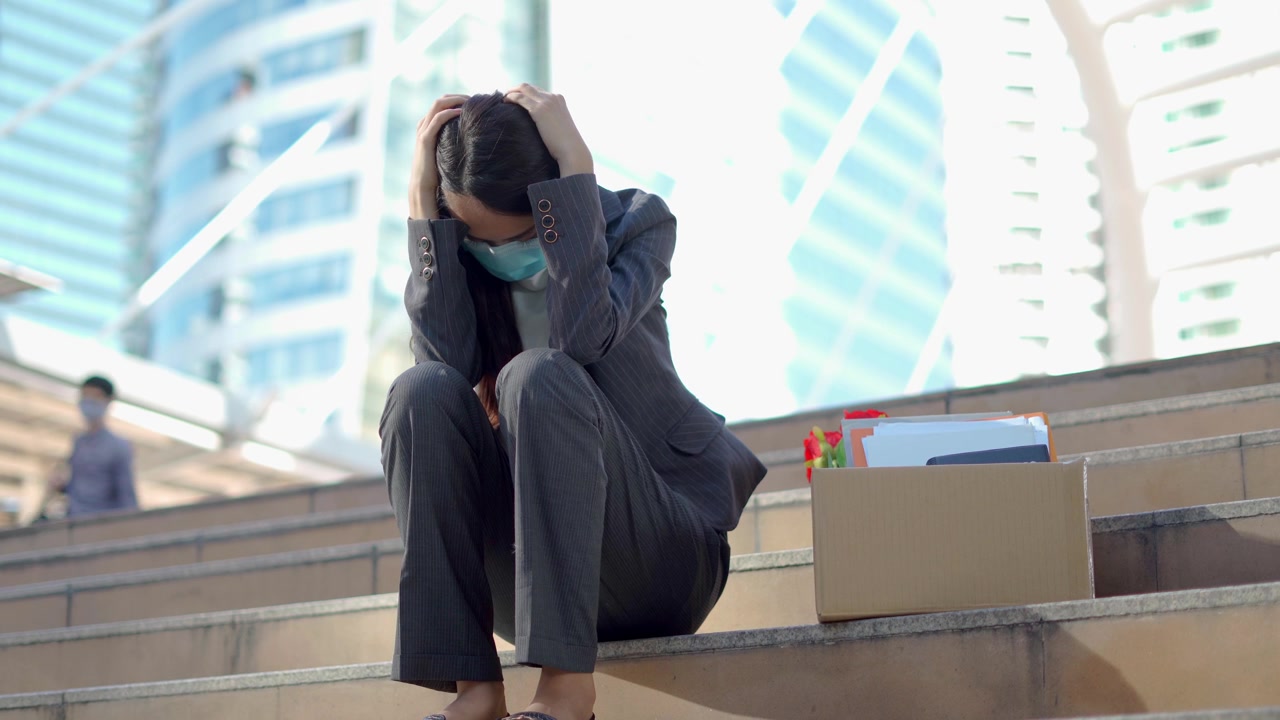 详情图-在公司裁员后，一个沮丧的女人拿着一个装着办公用品的盒子