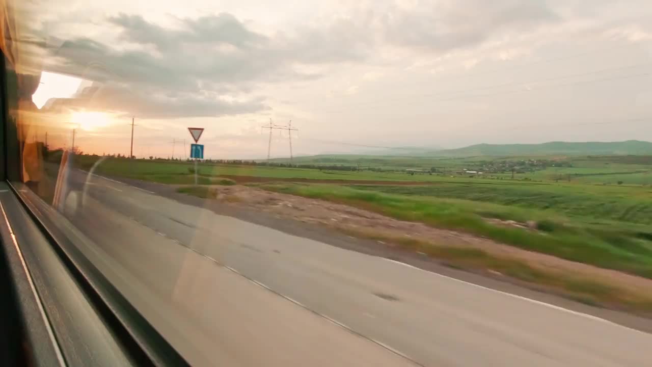 从移动的公共汽车上看到日落时自然景观的窗口。观光旅游。在高加索农村度假。乔治亚州的乡村