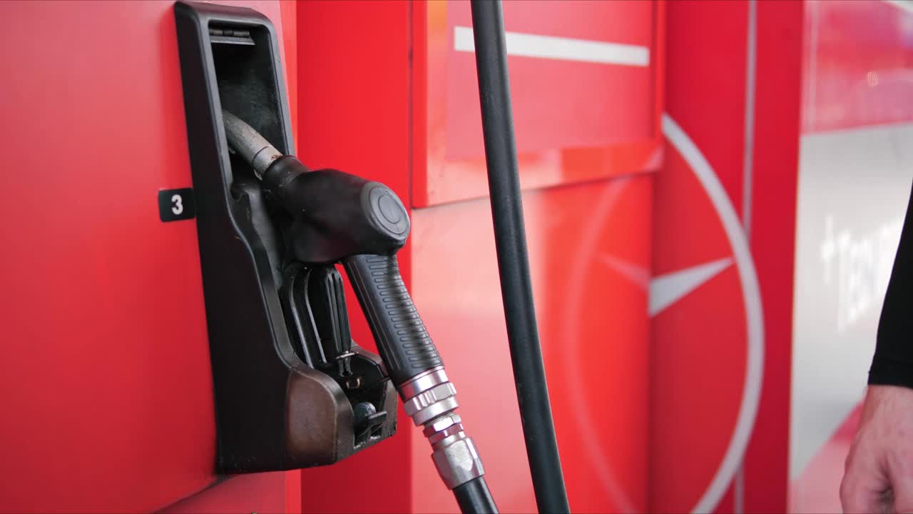 在加油站，手持加油嘴給汽車加油