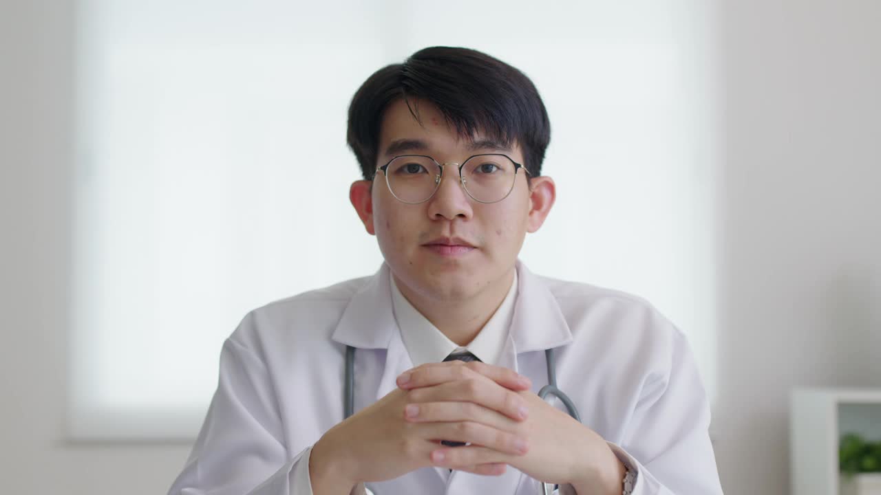 POV友好的亚洲男医生视频通话在线交谈看着摄像机。