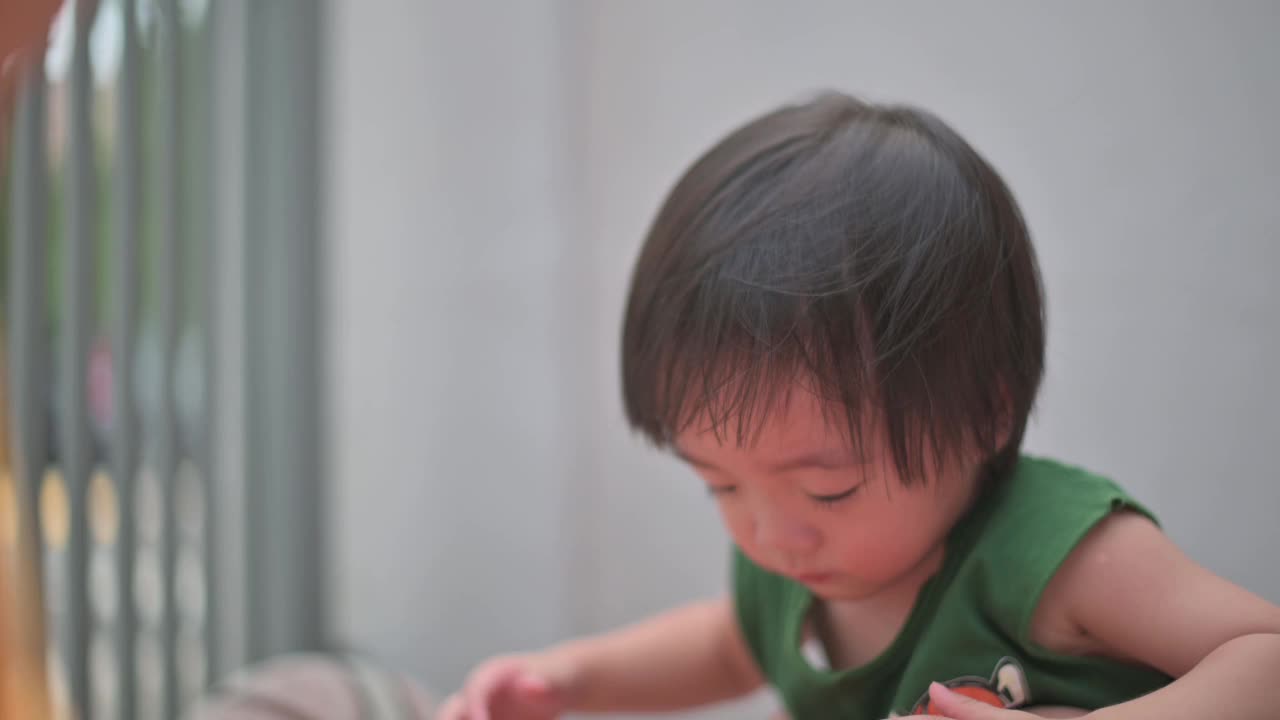 亚洲华人男婴在夏天的周末在房子前面玩球