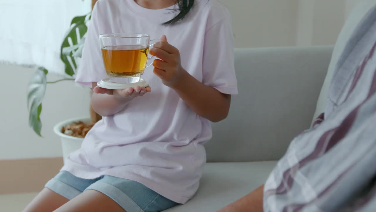 孙女正在客厅里给奶奶递一杯茶。