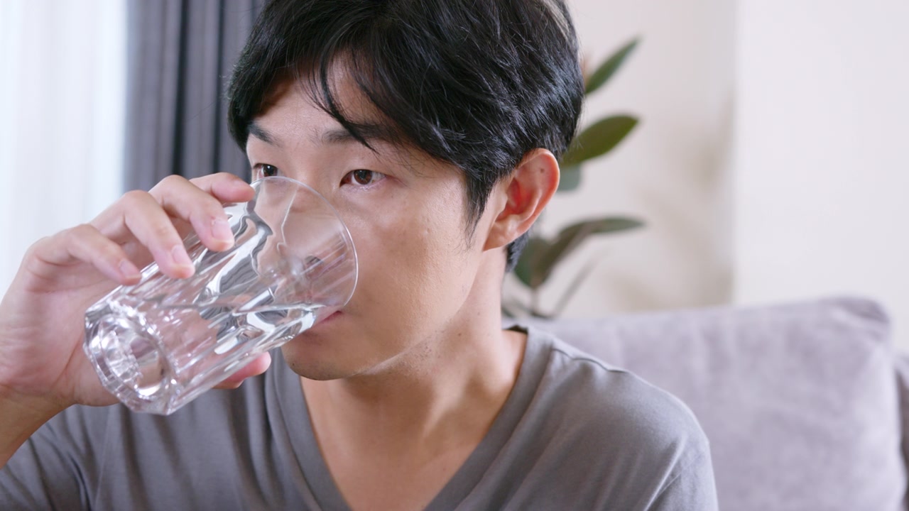详情图-成年男子坐在沙发上，一边喝着维生素和补品。健康的医学