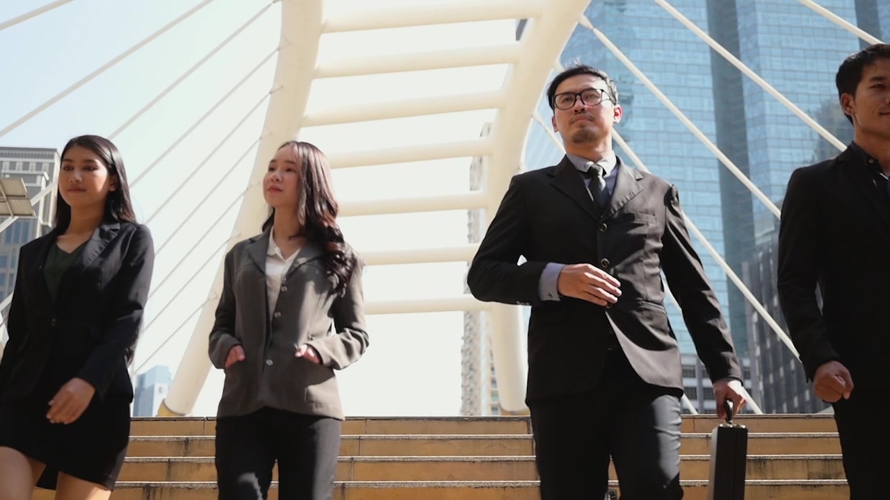 详情图-慢动作镜头。一群穿着西装的亚洲商人走下楼梯去上班。