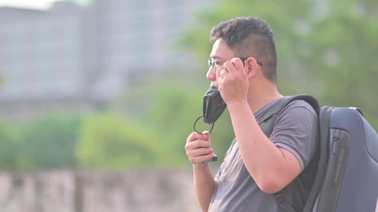 详情图-亚洲华人中年男子戴着口罩，在户外用哮喘吸入器背着背乞讨