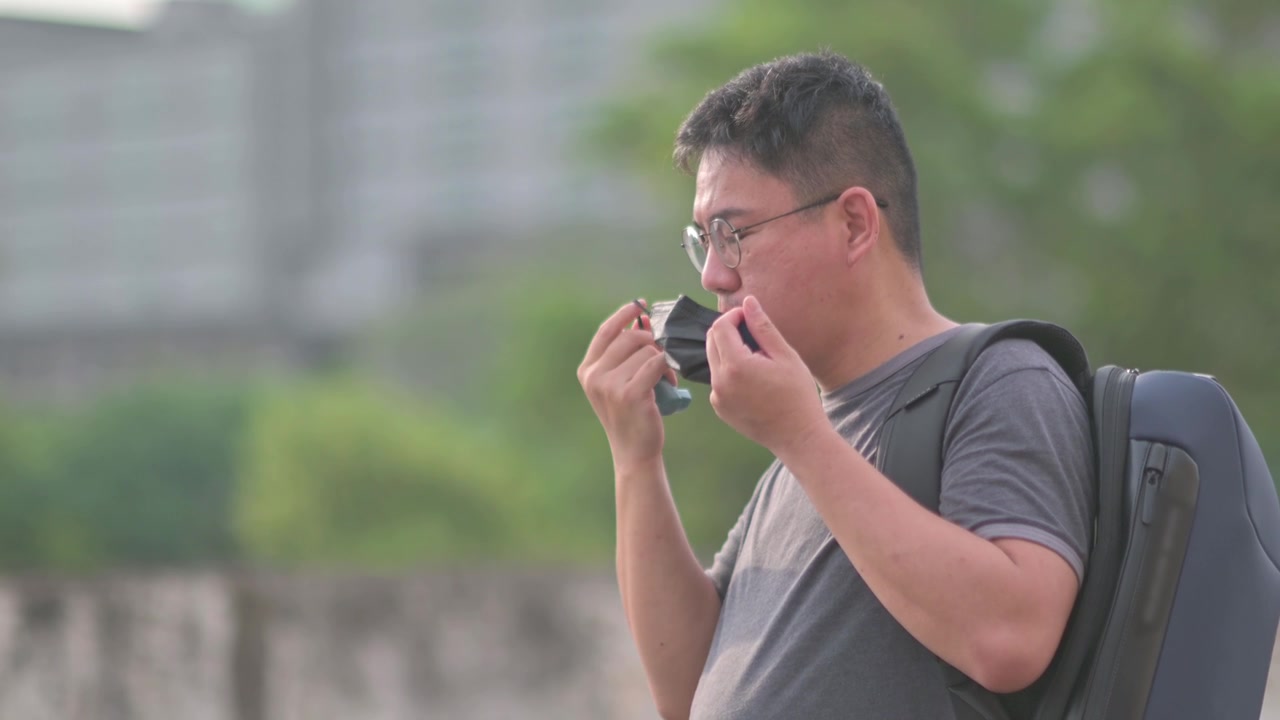 详情图-亚洲华人中年男子戴着口罩，在户外用哮喘吸入器背着背乞讨