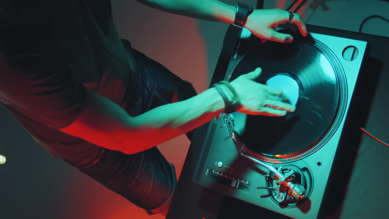 在夜总会派对上，Dj在调音台上播放电子音乐。dj手摸黑胶，滑块。俯视图