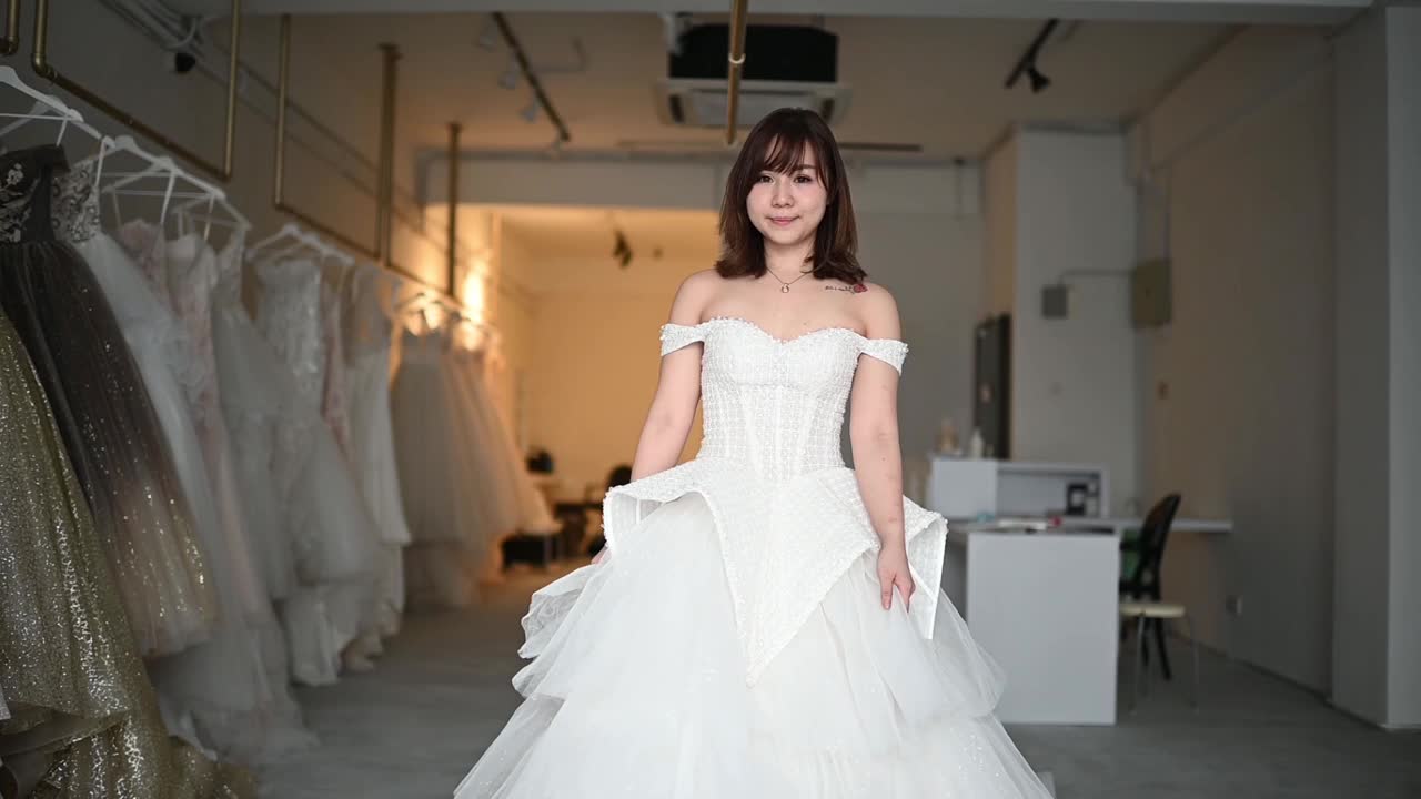 慢动作新娘肖像摆姿势看着相机微笑在婚纱店尝试结婚礼服长大