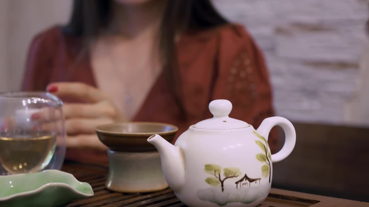 东方饮茶文化。中国饮茶仪式上，桌上有泡茶设备。喝中国乌龙茶或白茶的妇女