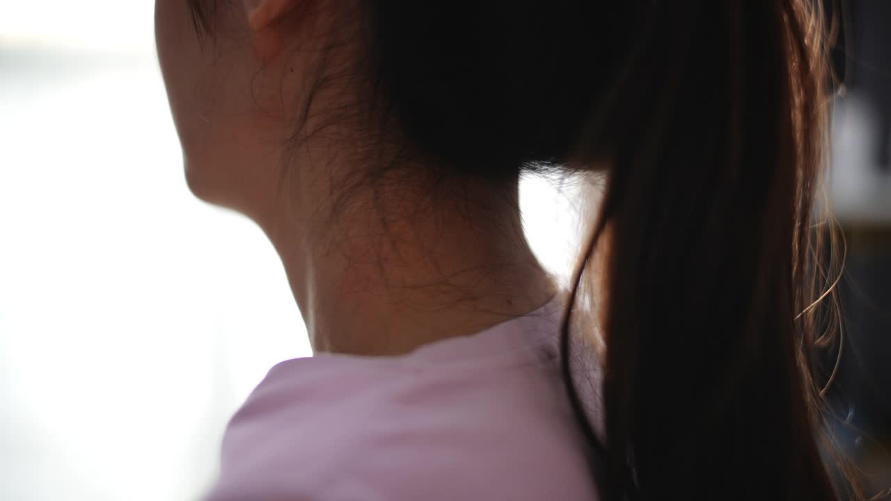 亚洲妇女在家里因压力而揉脖子