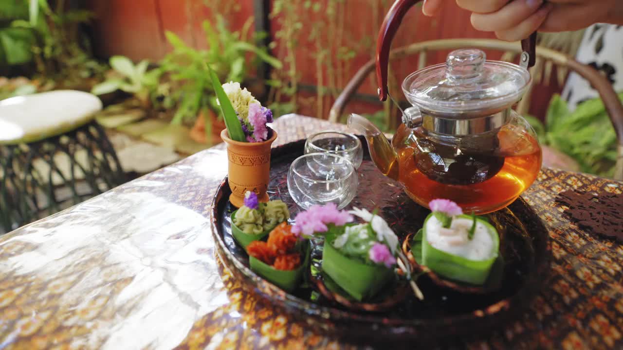 透明茶杯中的花草茶，搭配Khanom Tako，泰式椰子布丁，Khanom Chan，泰式分层甜点，