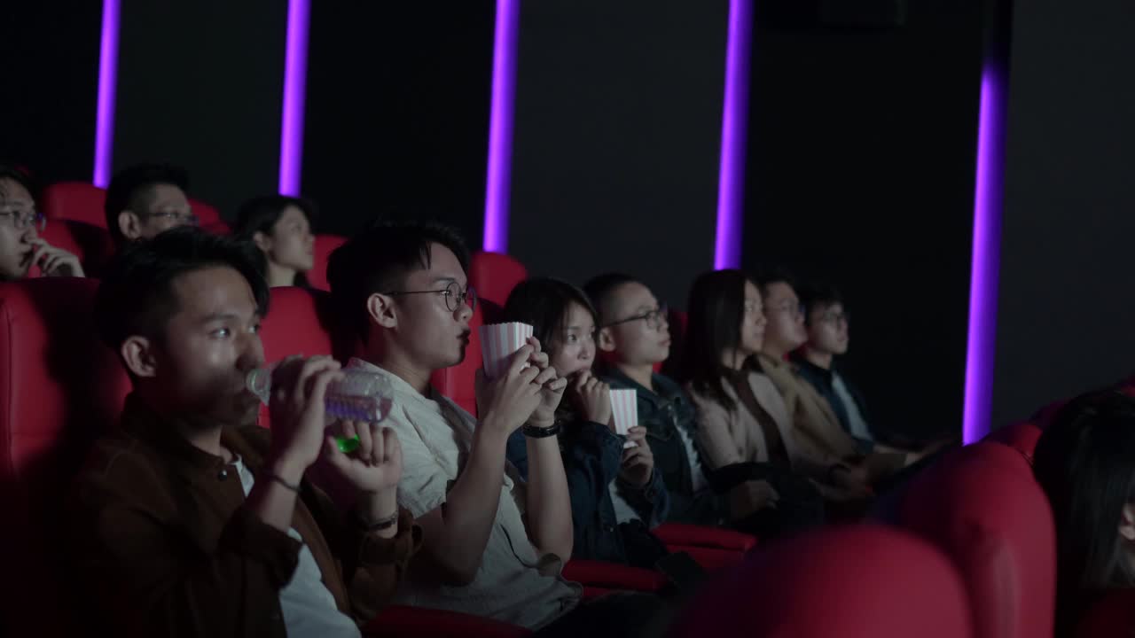 一名亚裔中国年轻人不小心把爆米花倒向了其他观众，吓了一跳