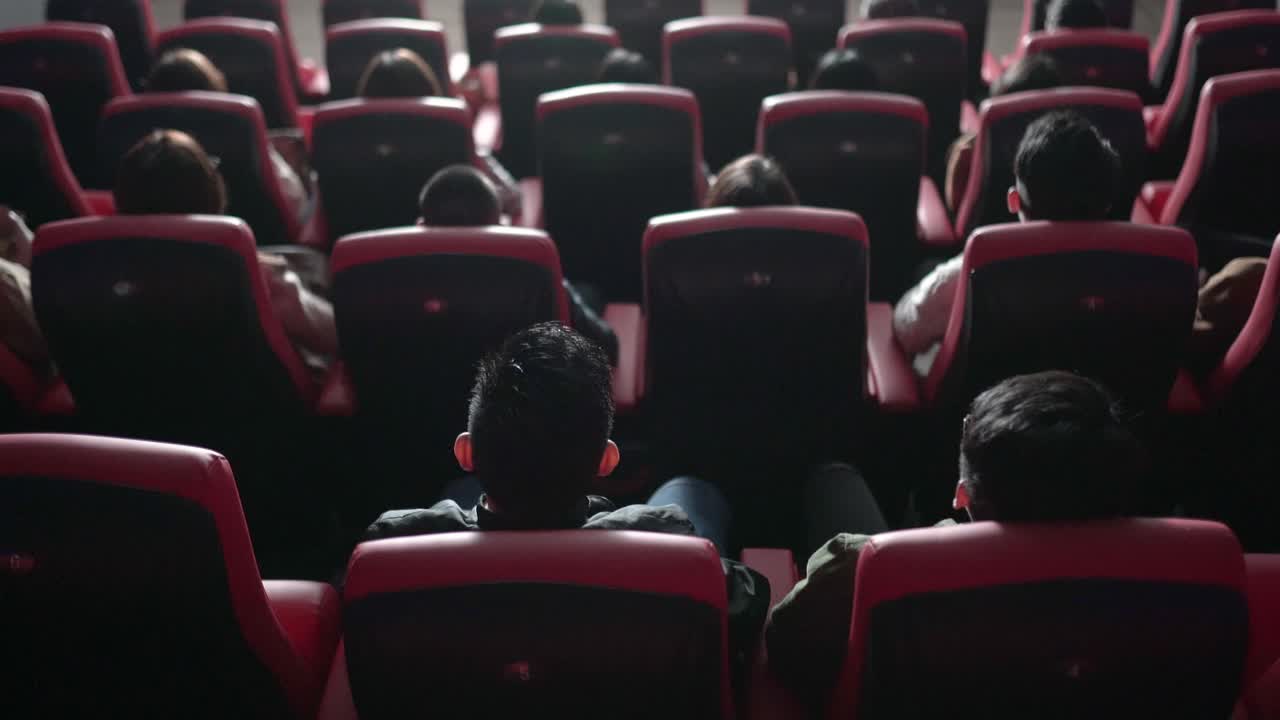后视组亚洲观众在电影院观看3D电影，戴上3D眼镜欣赏演出