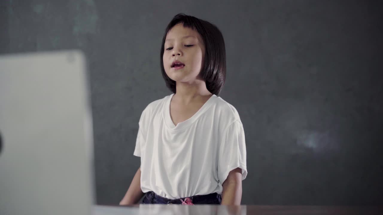 小女孩看着笔记本电脑，在客厅里唱歌。