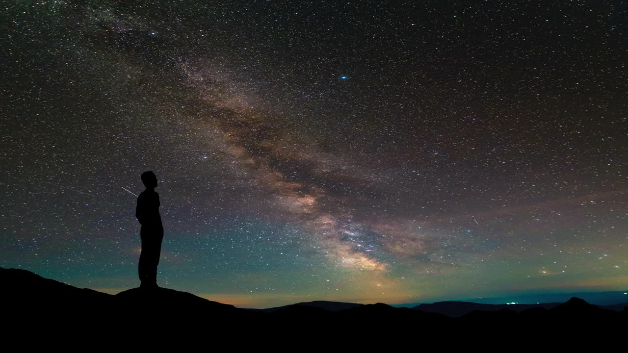 孤独的人站在繁星满天的山顶。间隔拍摄