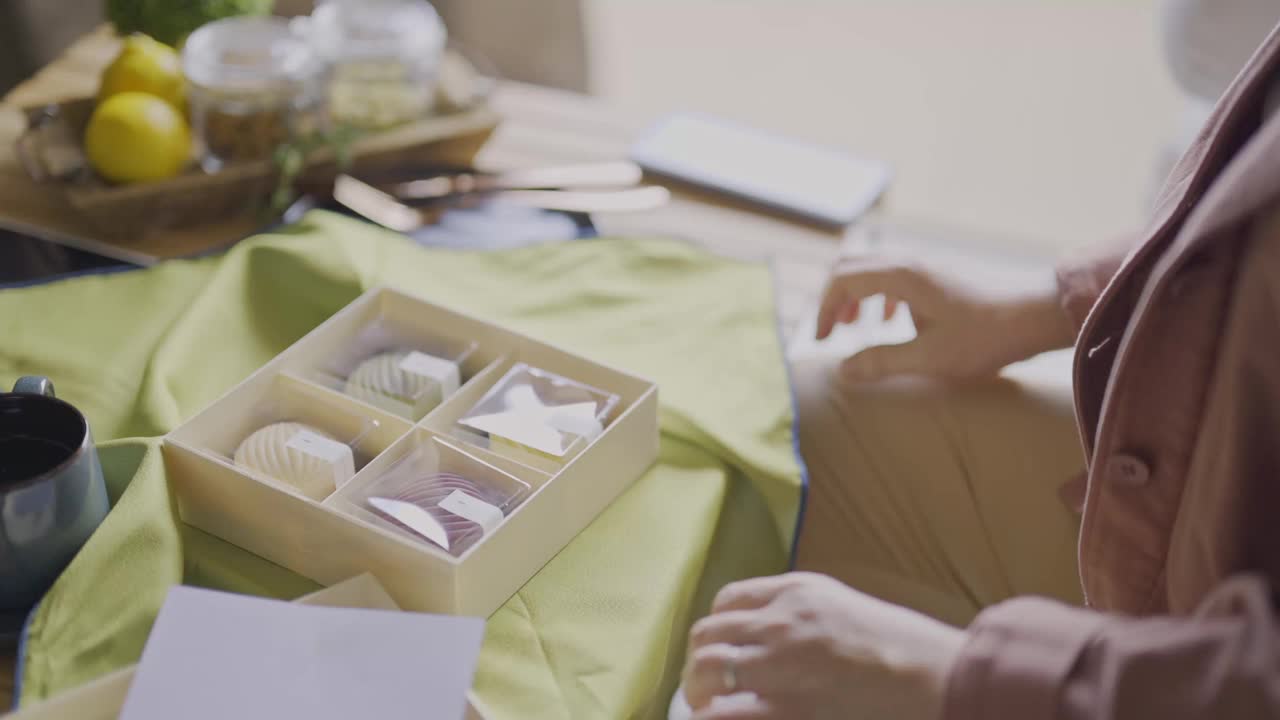 亚洲中国女子在客厅用智能手机拍摄朋友送的月饼礼盒