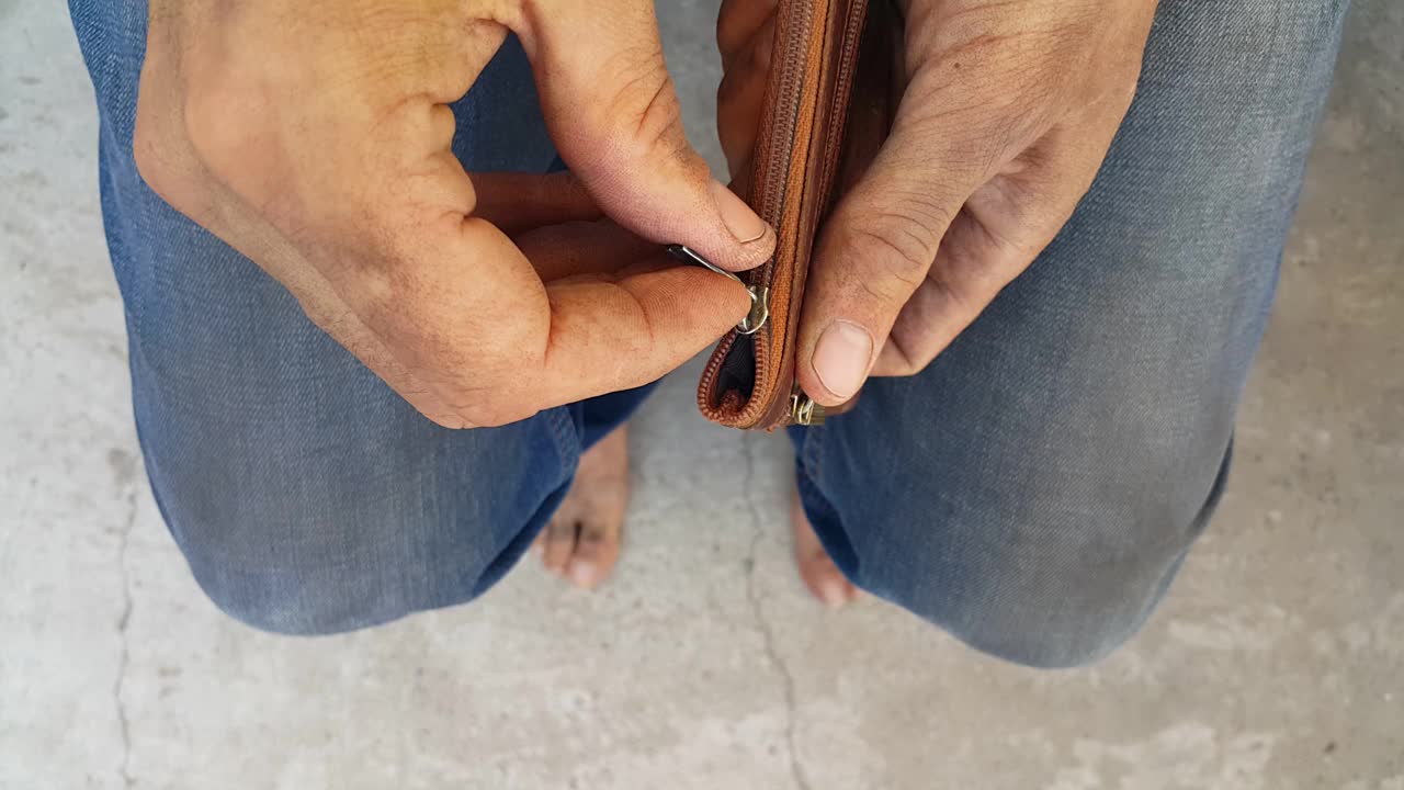 一个无家可归的穷人用肮脏的双手发现他的钱包是空的。一个失业的人。公司破产。贫穷和苦难。公民的需要。饥饿和寒冷。光着脚，没有焦点。