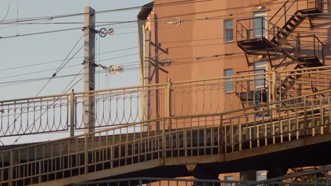 一辆电动火车正从一座铁路桥上驶过，这座铁路桥位于城市的居民楼之间。