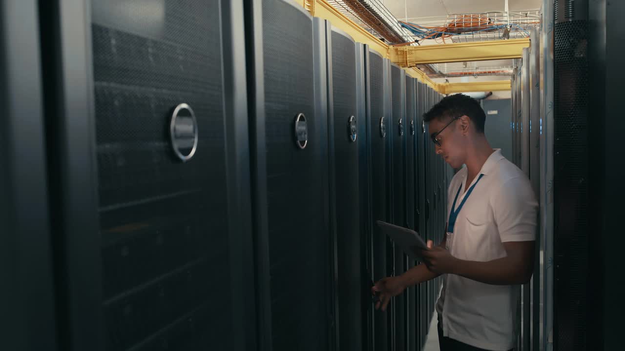 一名年轻技术人员在服务器室进行维修检查时使用技术的4k视频片段