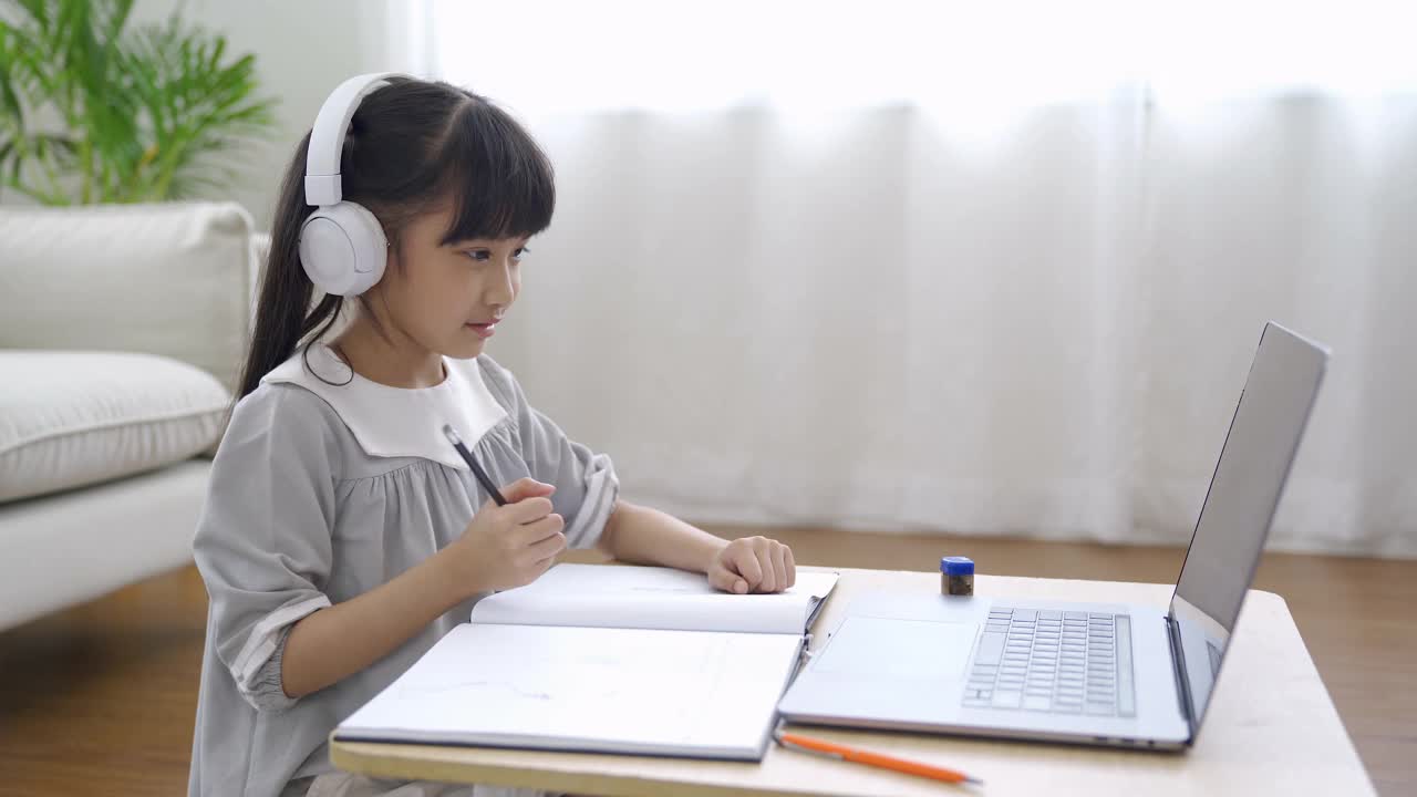亚洲女孩用笔记本电脑做作业。