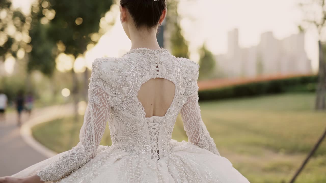 年轻美丽的亚洲新娘穿着白色婚纱，漫步在花园中，从后面拍摄，慢动作
