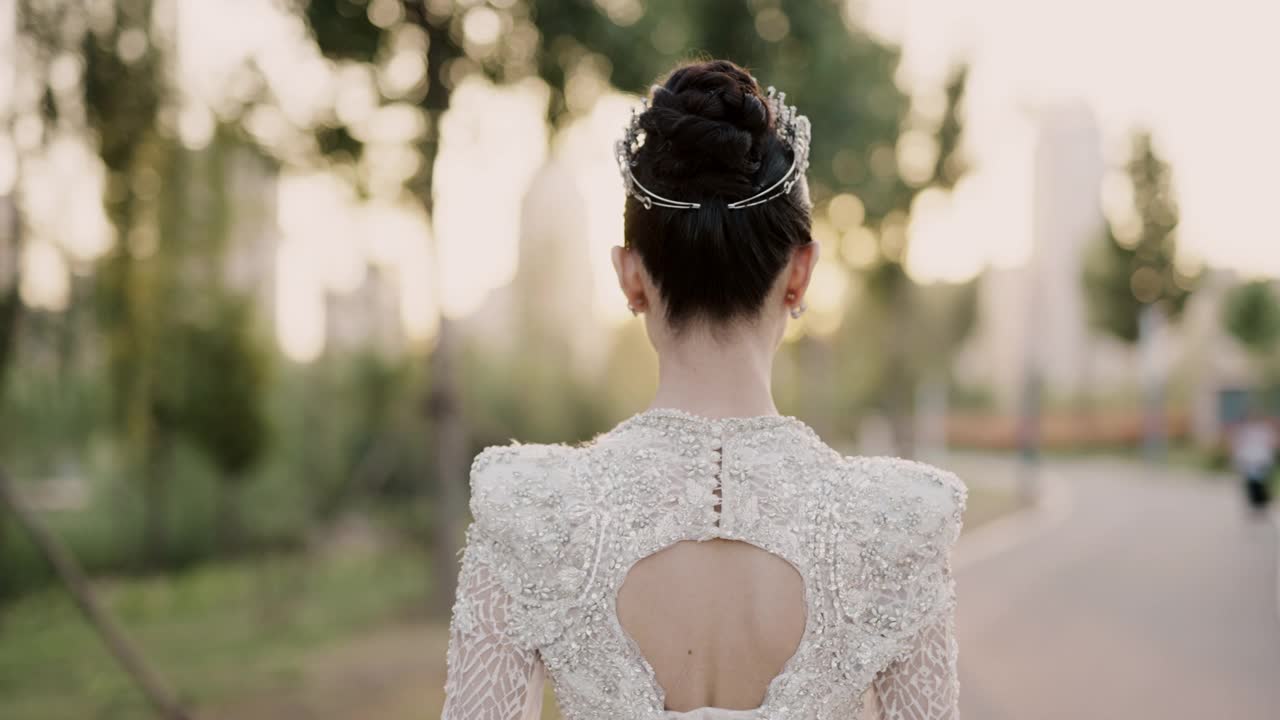 年轻美丽的亚洲新娘穿着白色婚纱，漫步在花园中，从后面拍摄，慢动作