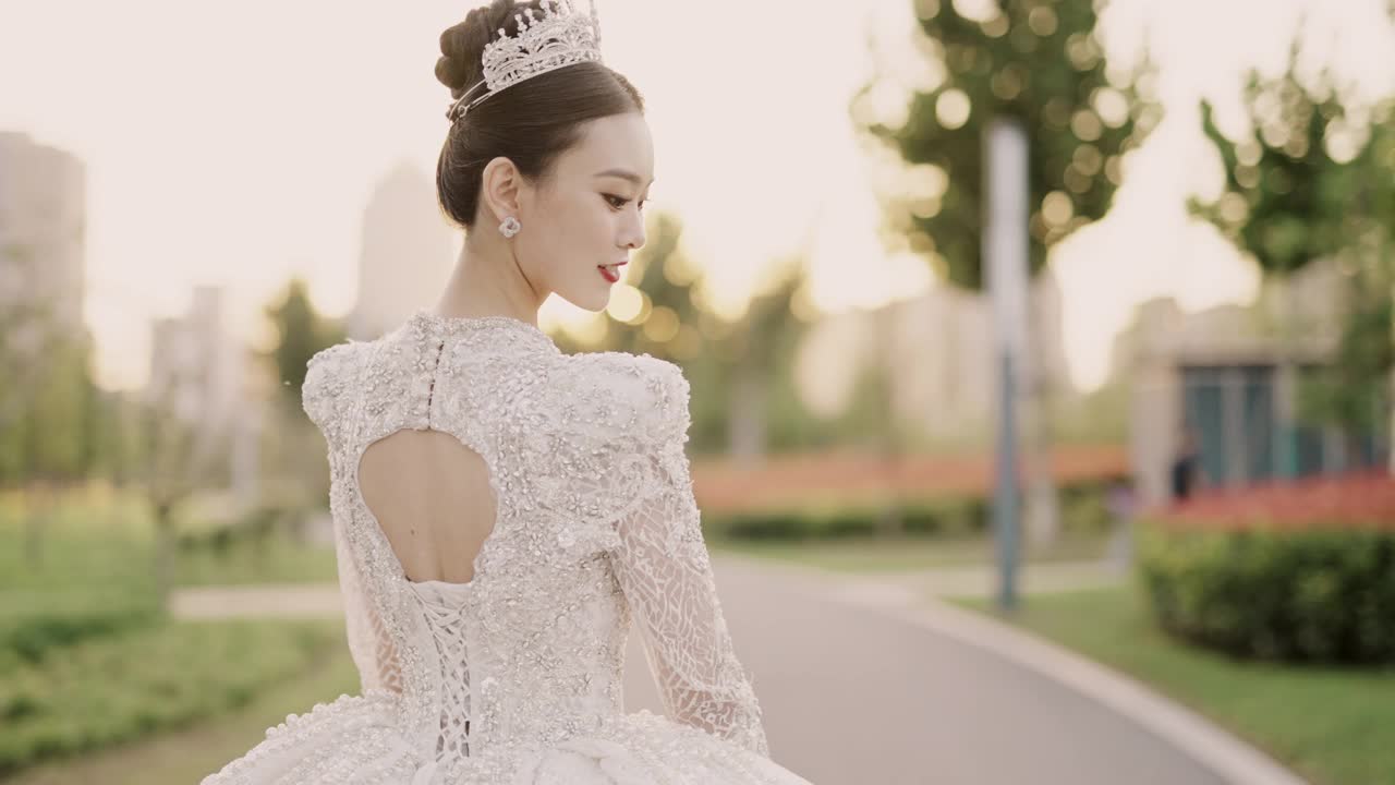 年轻美丽的亚洲新娘穿着白色婚纱，漫步在花园中，从后面拍摄，慢动作