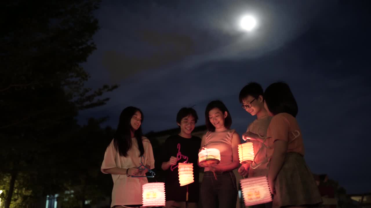 亚洲华人妈妈带着孩子和侄子拿着纸灯笼，庆祝中秋节。
