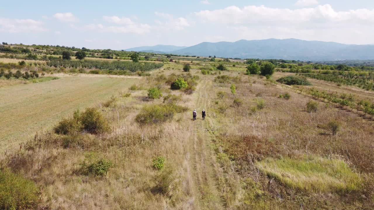 两个人走过塞尔维亚南部的果园