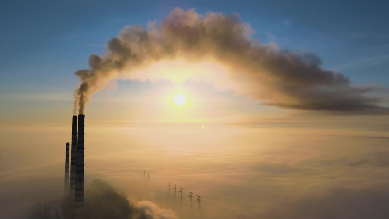 鳥瞰圖的煤電廠高管道與黑煙上升污染大氣在日落。