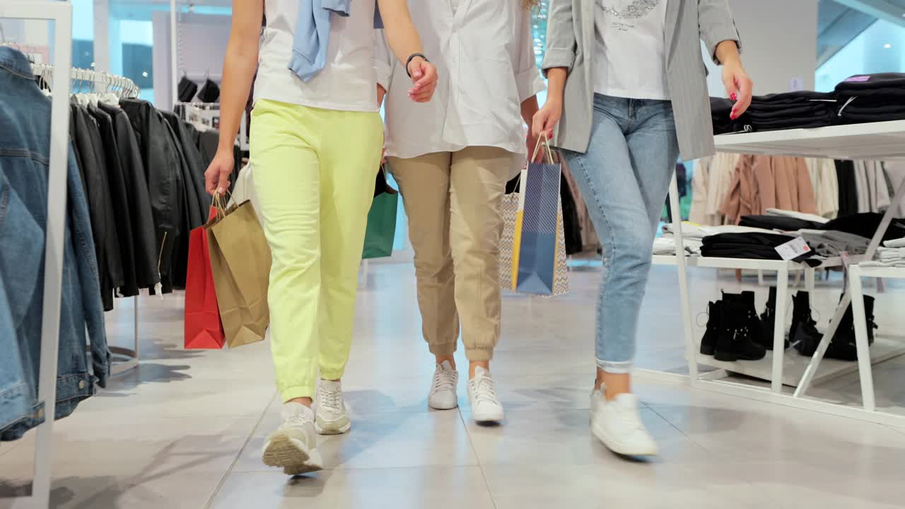 照片中的女性腿穿着五颜六色的衣服走过商场。青年生活方式、友谊和消费观念。购物后隔离。