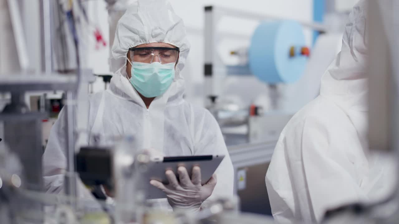 工程师工人在PPE套件质量控制自动化制造医疗口罩预防冠状病毒。