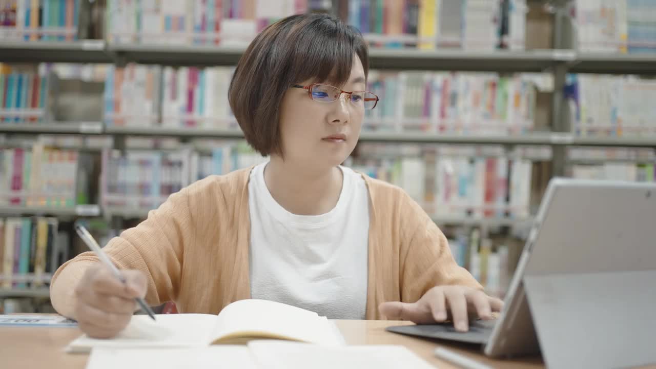 亚洲女人在图书馆用笔记本电脑