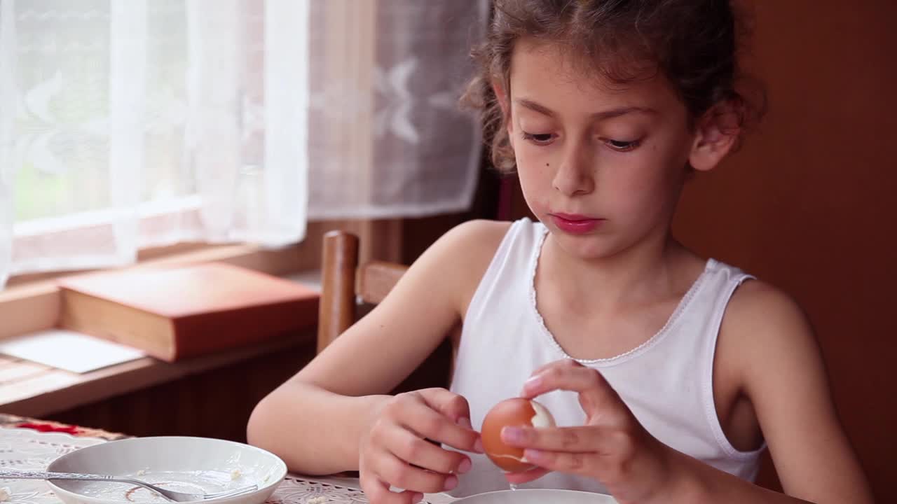 快乐的小女孩在餐桌上剥煮鸡蛋