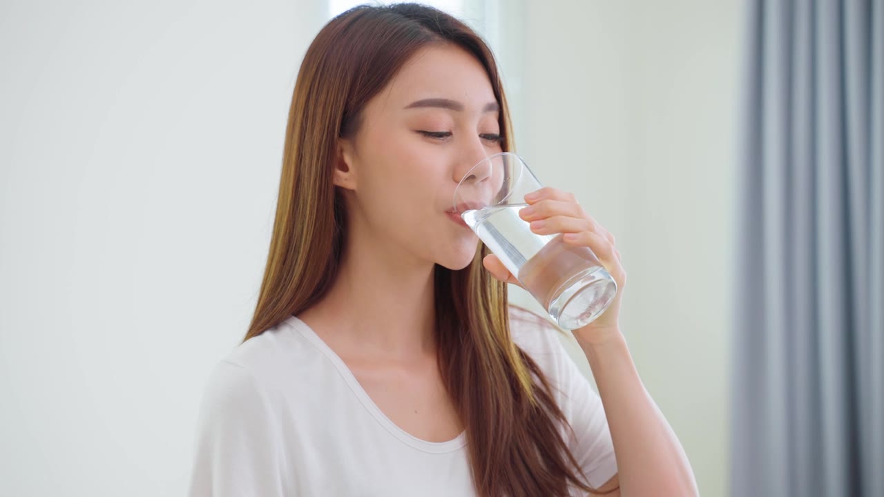 詳情圖-亞洲美女坐在床上，在臥室里喝一杯水。年輕干渴的美麗女孩在清晨醒來后抱著干凈的礦物自然杯，在家中為保健啜飲。