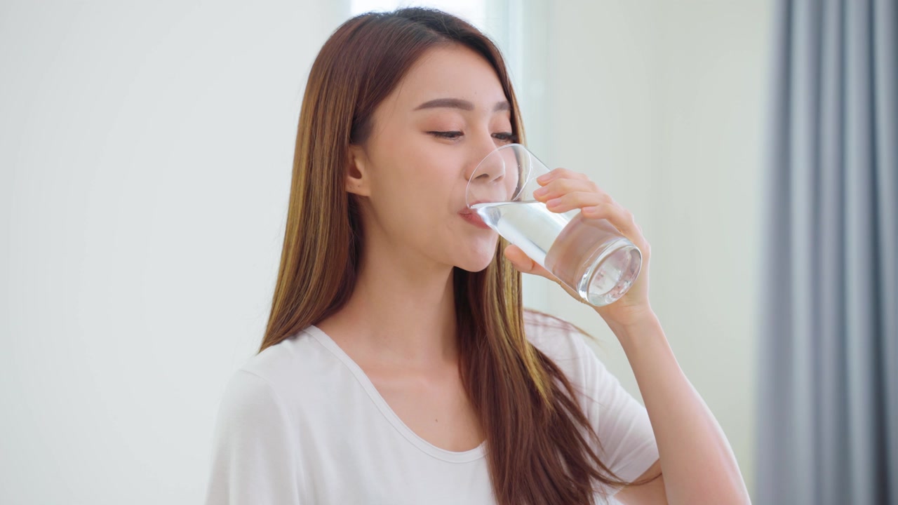 詳情圖-亞洲美女坐在床上，在臥室里喝一杯水。年輕干渴的美麗女孩在清晨醒來后抱著干凈的礦物自然杯，在家中為保健啜飲。