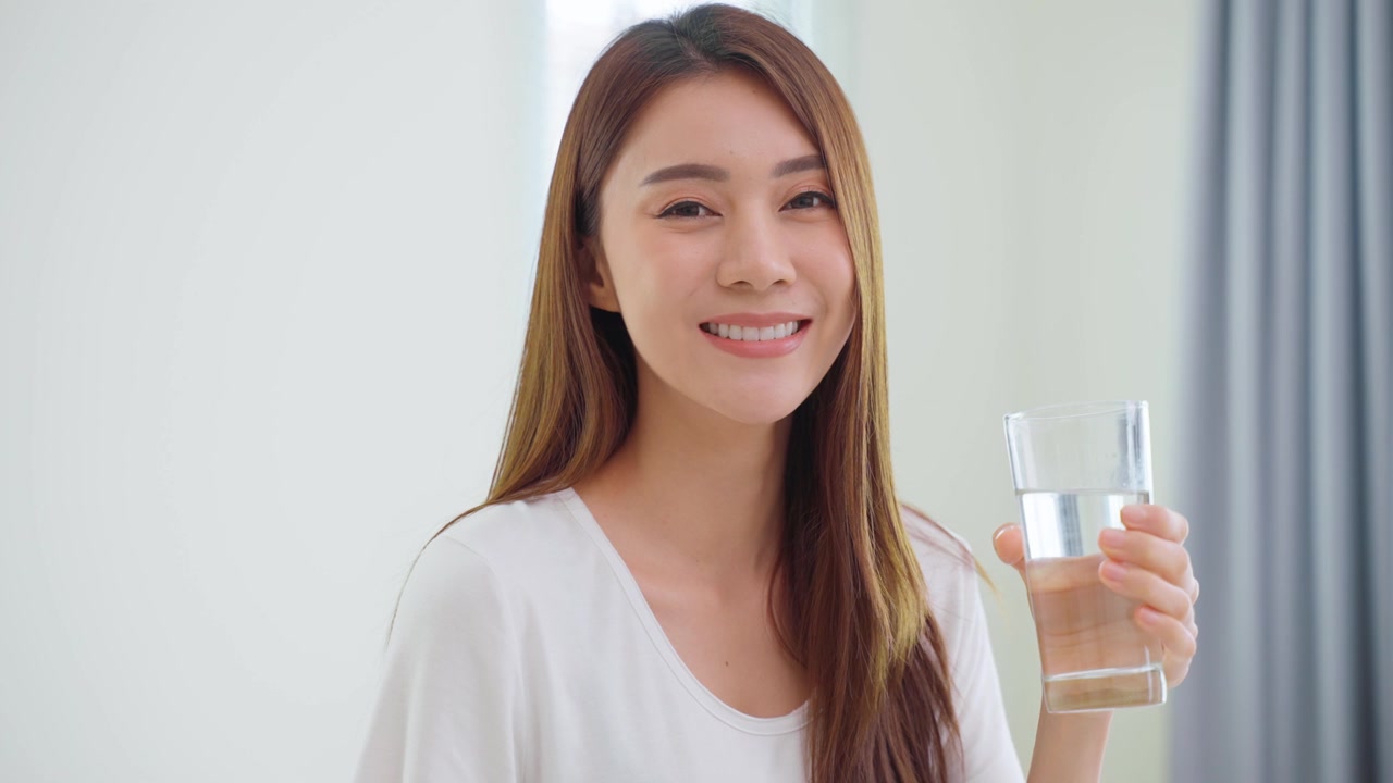 詳情圖-亞洲美女坐在床上，在臥室里喝一杯水。年輕干渴的美麗女孩在清晨醒來后抱著干凈的礦物自然杯，在家中為保健啜飲。