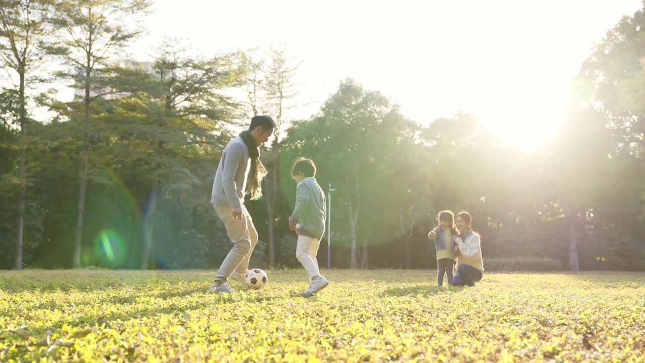 一个亚洲小男孩和爸爸在公园里踢足球