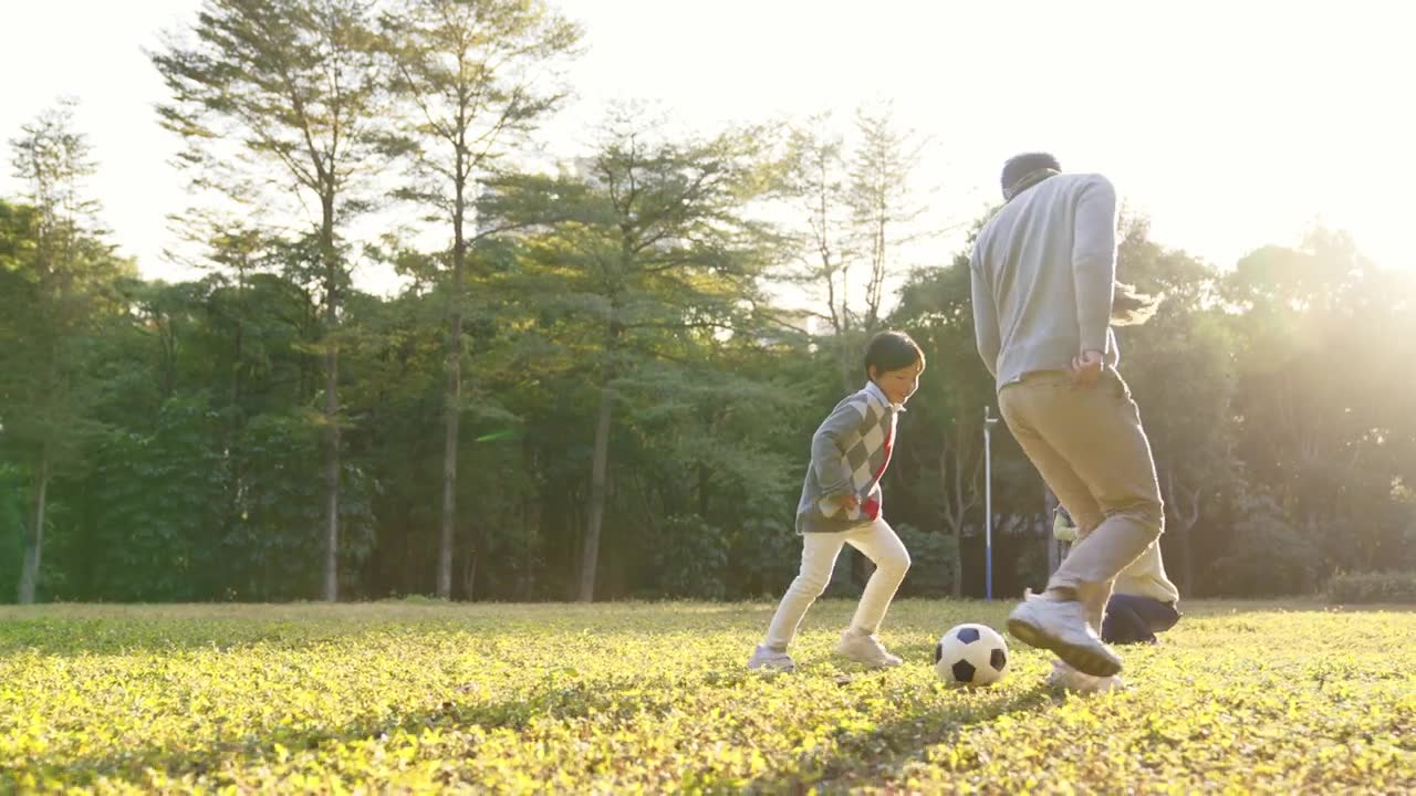 詳情圖-一個(gè)亞洲小男孩和爸爸在公園里踢足球