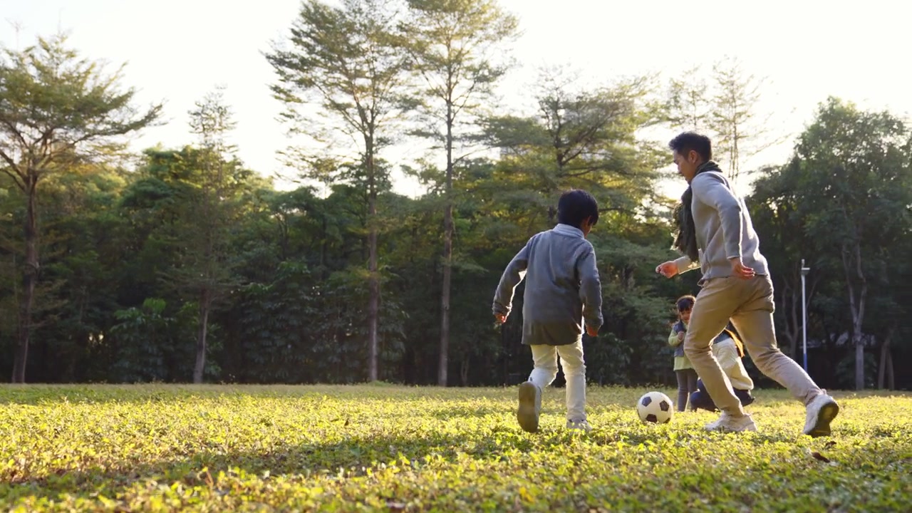 詳情圖-一個(gè)亞洲小男孩和爸爸在公園里踢足球
