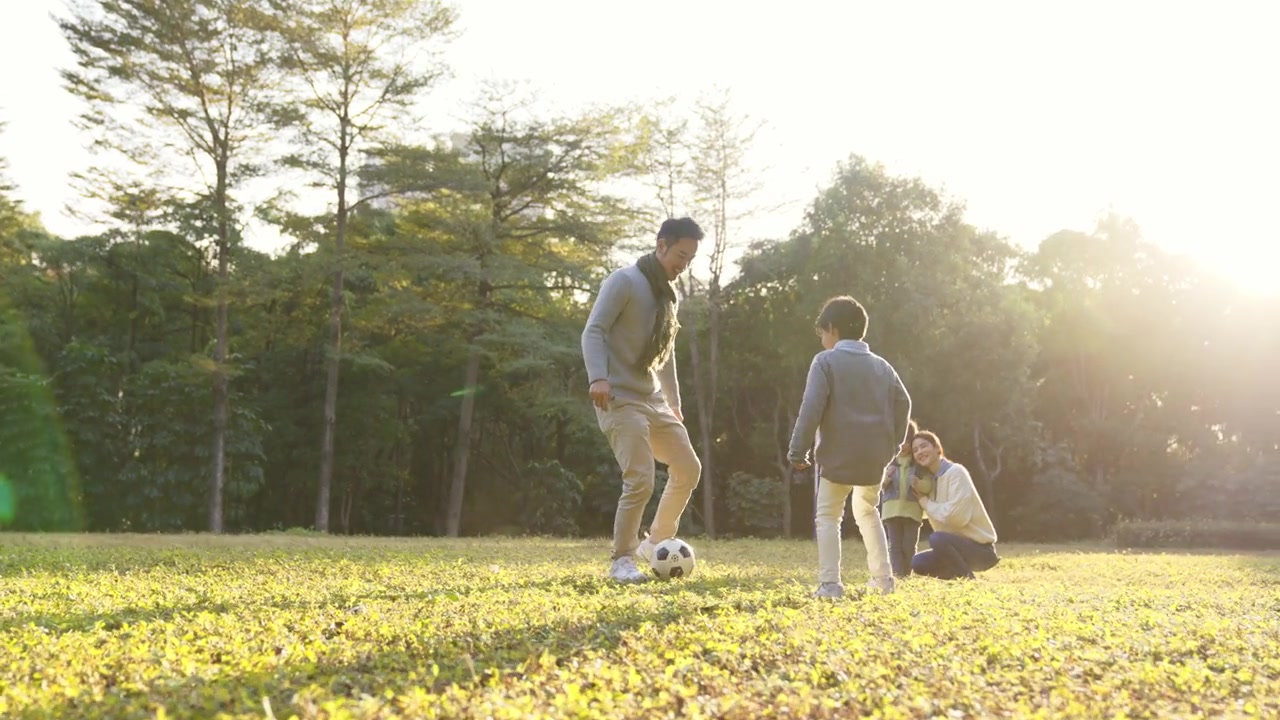 詳情圖-一個(gè)亞洲小男孩和爸爸在公園里踢足球