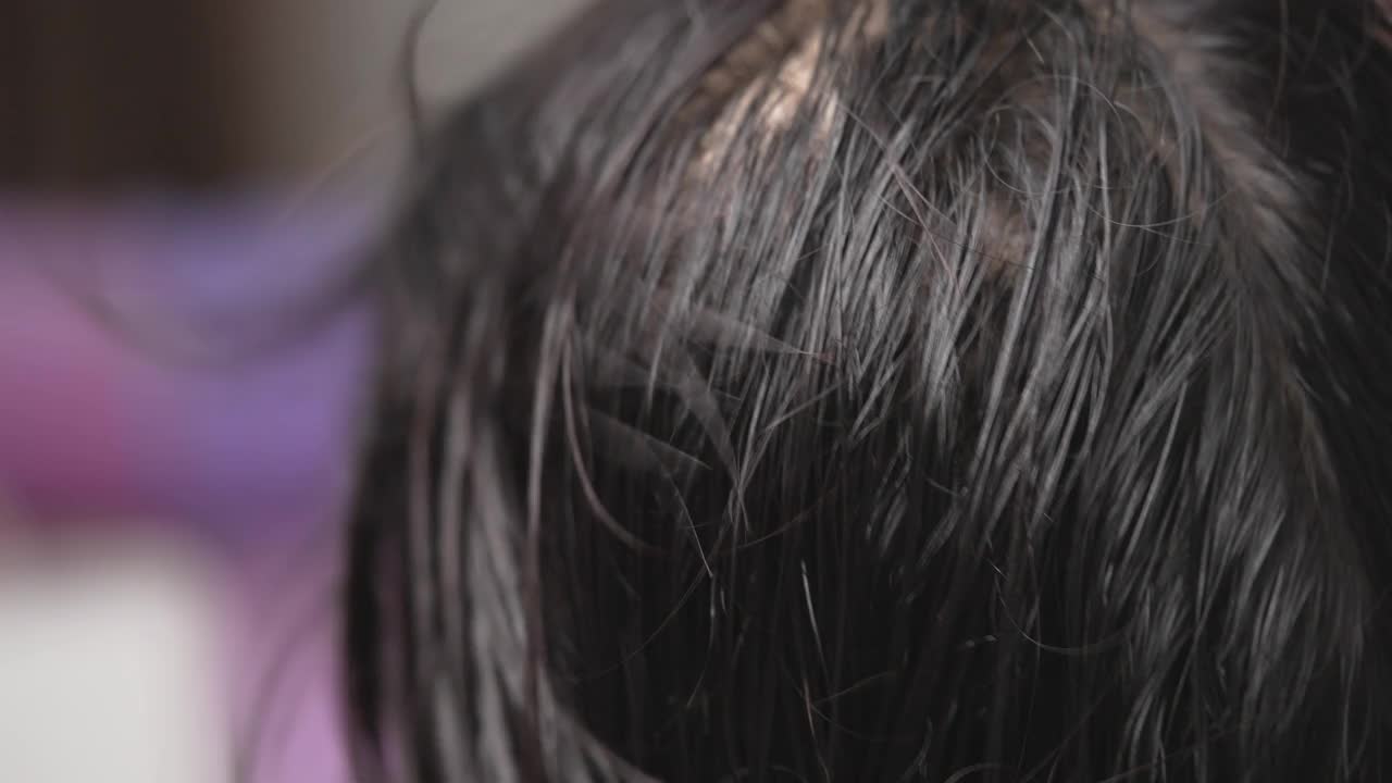 一位中年亚洲妇女在家里用吹风机吹头发