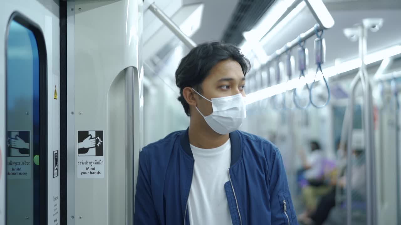 亚洲男子在地铁上戴口罩。