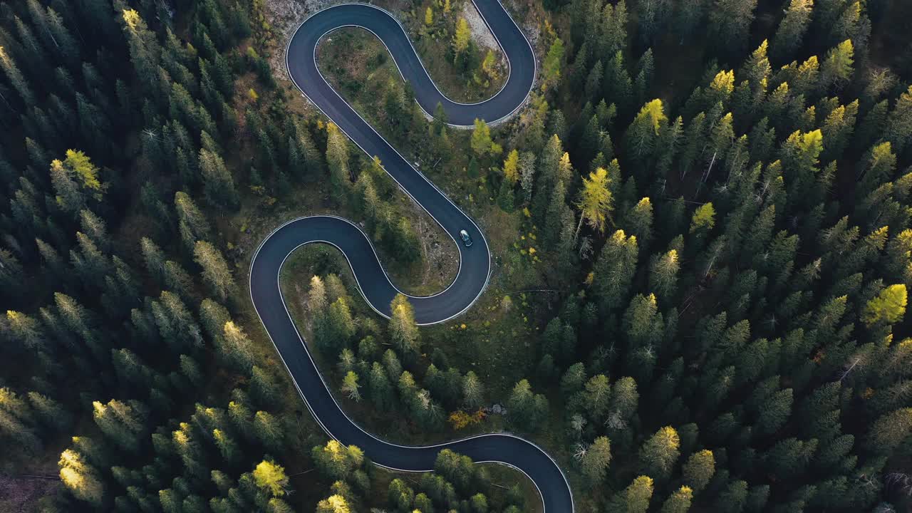 鸟瞰图的汽车驾驶曲折的山路穿过秋天的森林